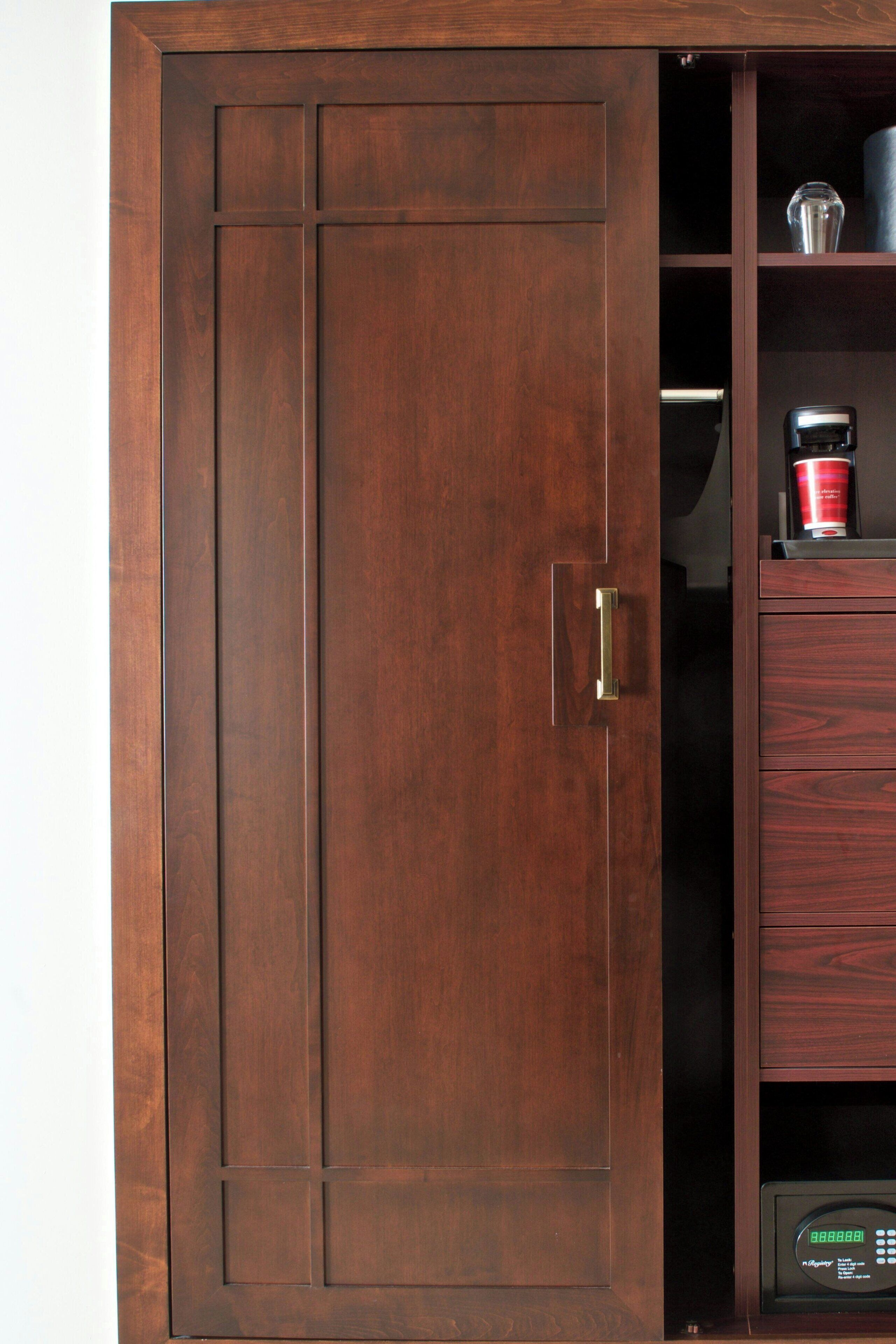 Un mueble de madera con cerradura digital y una cafetera encima.