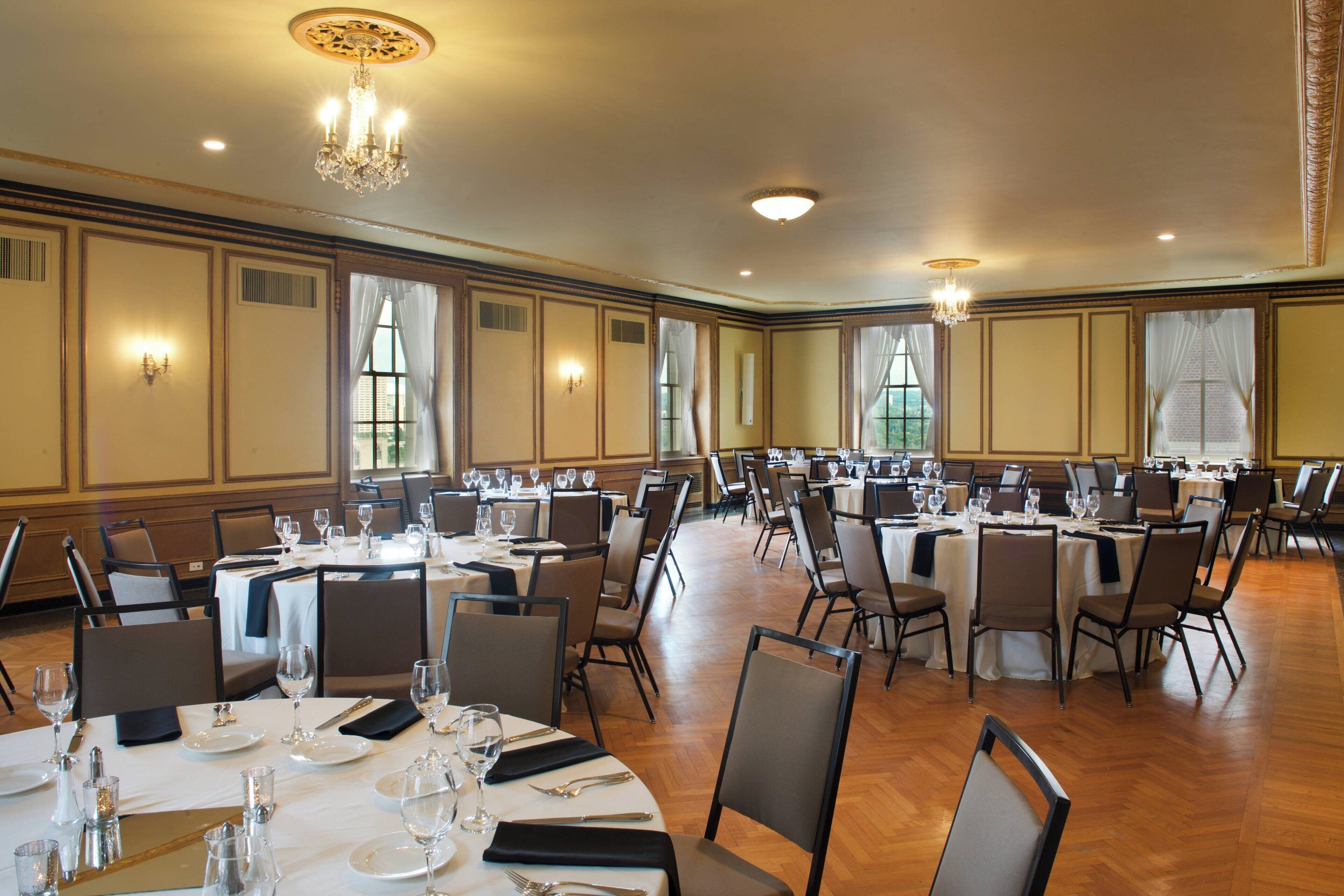 A banquet hall with multiple round tables set for dining, equipped with chairs and table settings.