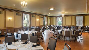 A banquet hall with multiple round tables set for dining, equipped with chairs and table settings.