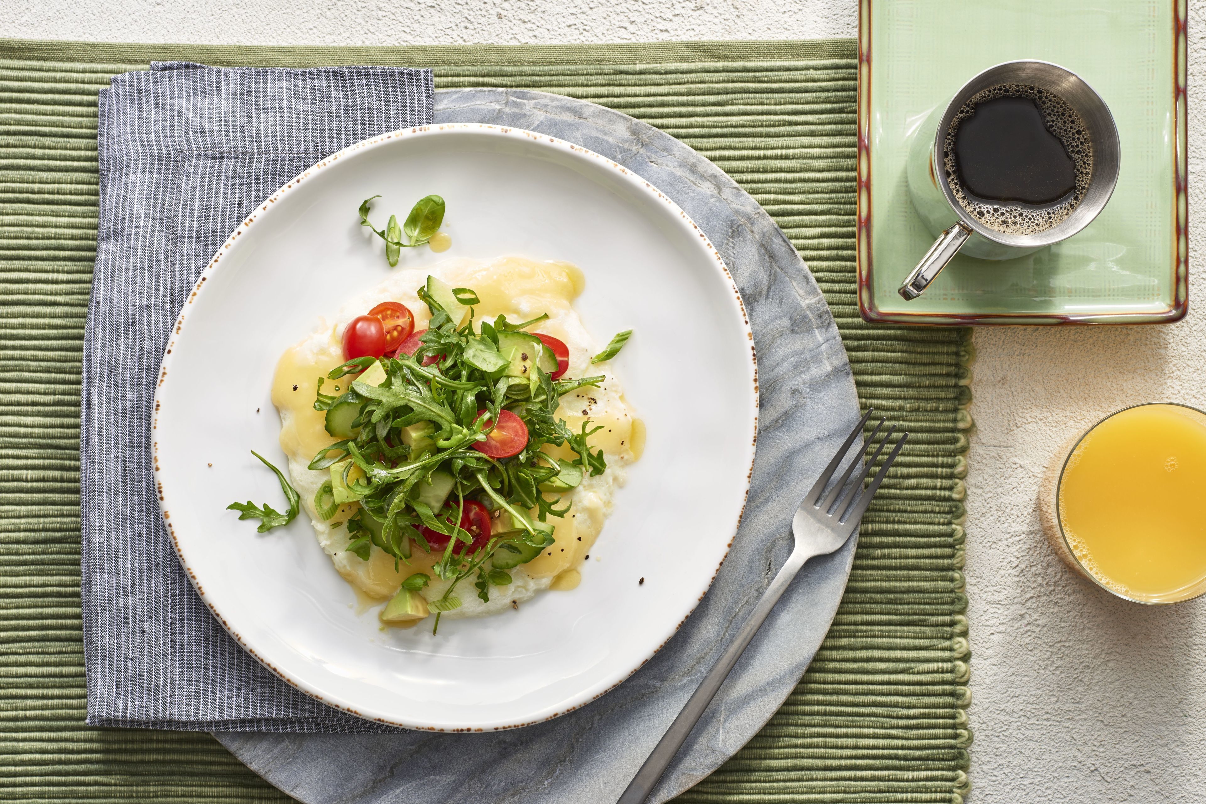 Une assiette de nourriture, avec une fourchette et une tasse de café, posée sur un set de table vert.