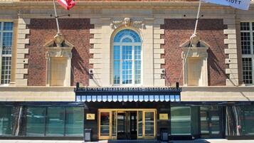 A brick building with a large arched window, a marquee sign, and an American flag.