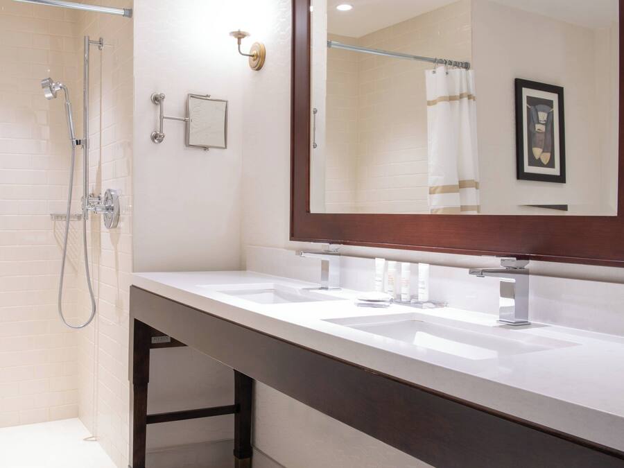 A modern bathroom with two sinks, a shower, and a large mirror.