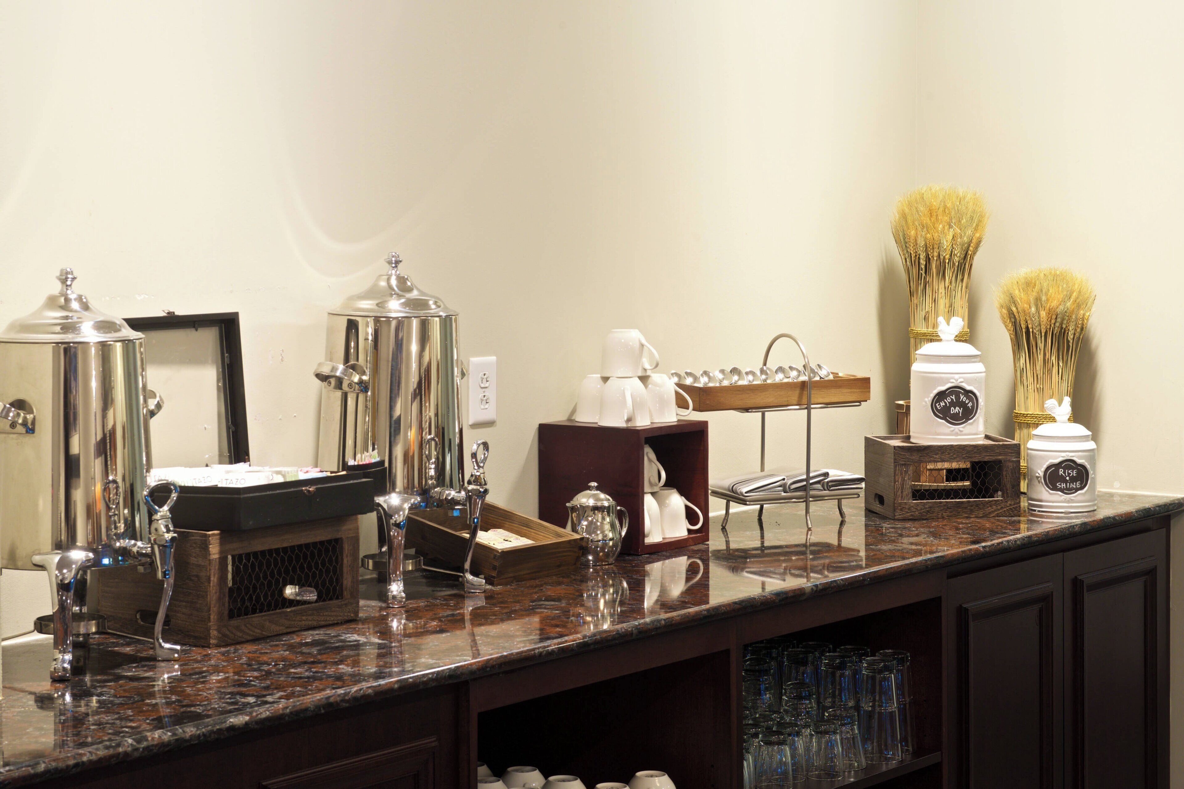 Eine Hotelbar mit Edelstahlgeräten, einer Kaffeestation und einer dekorativen Vase.