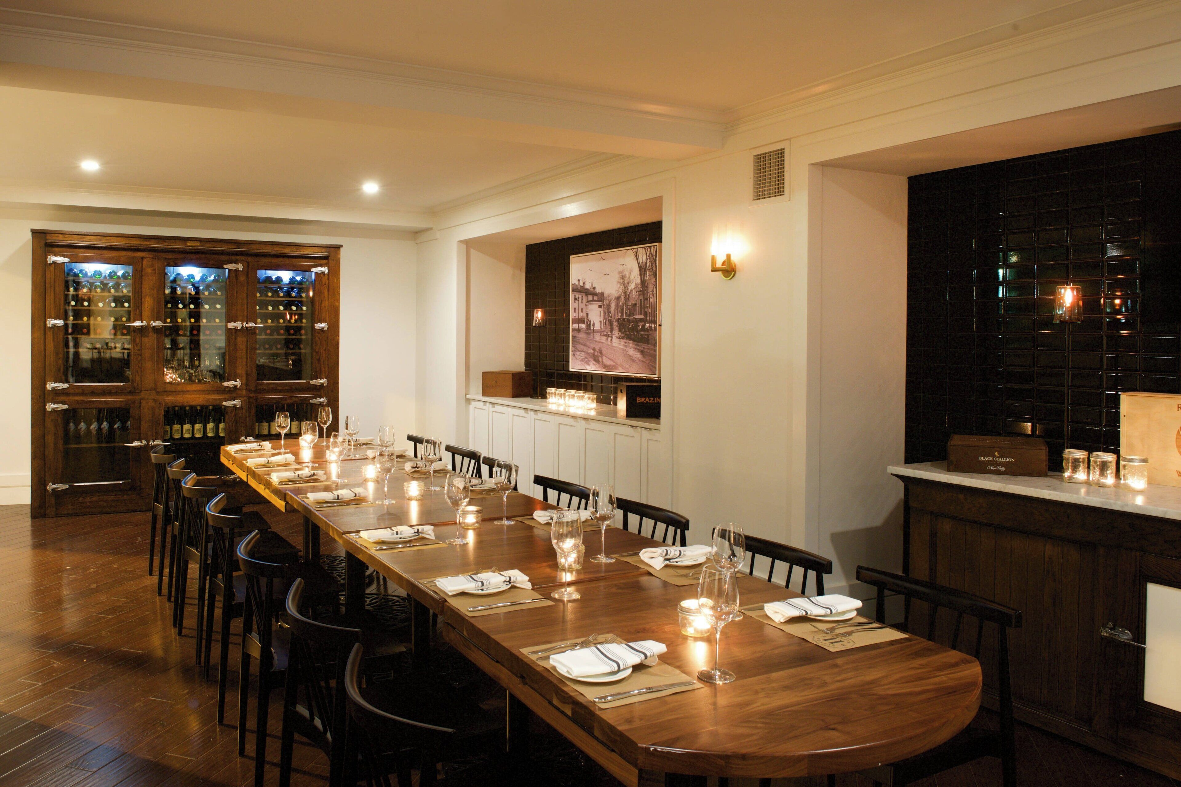 Una larga mesa de comedor dispuesta con sillas, una estantería para vinos y una zona de bar con mostrador.