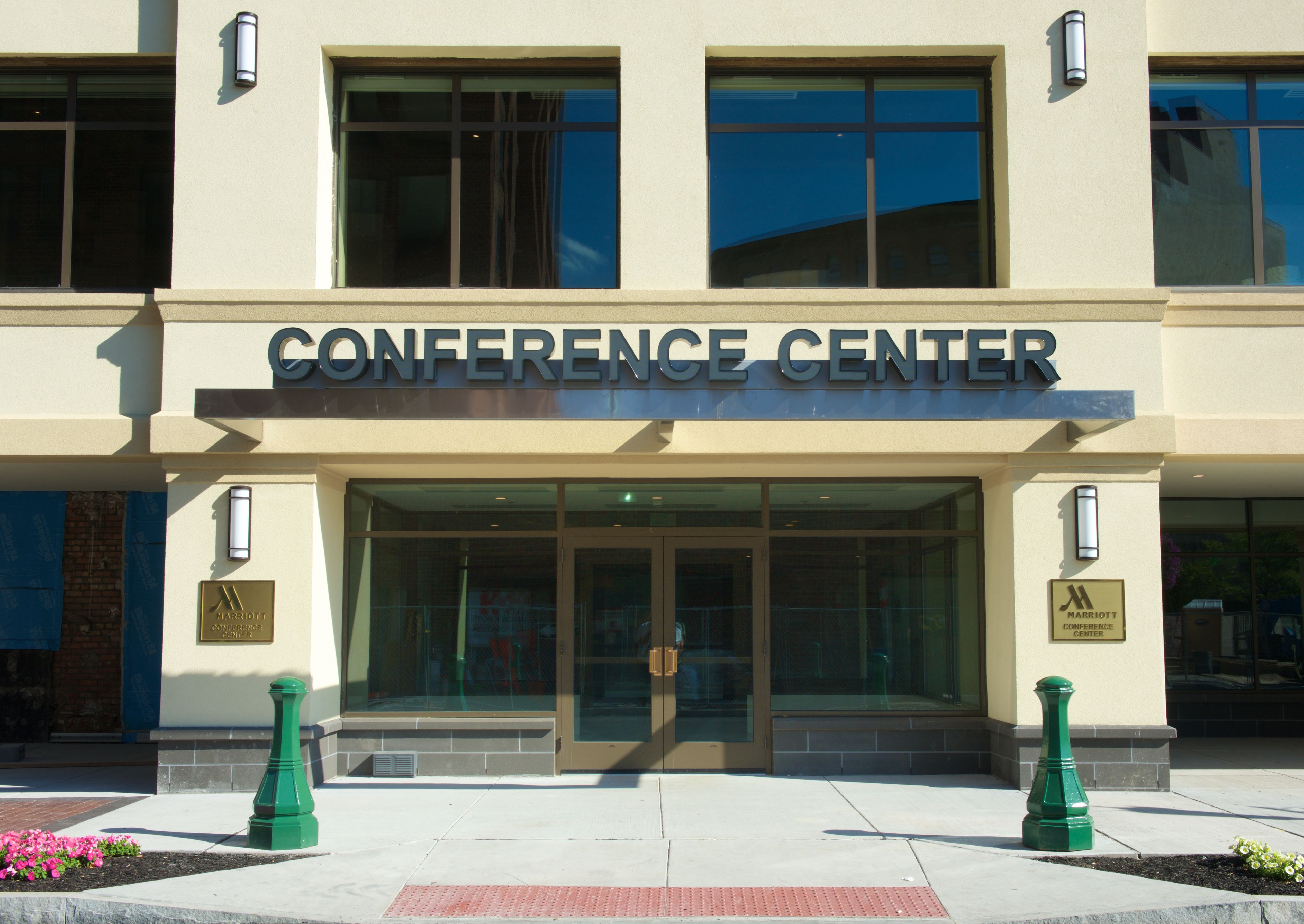 The exterior of a conference center with a large entrance, glass doors, and a sign above the doors.