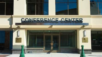 The exterior of a conference center with a large entrance, glass doors, and a sign above the doors.
