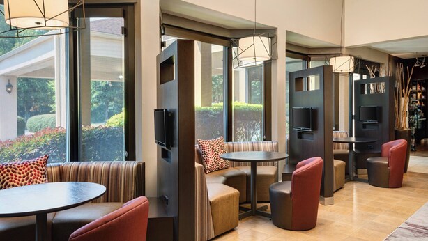 A modern lounge area with seating arrangements, a bar area, and a television screen. - Courtyard by Marriott - Atlanta Executive Park/Emory (Atlanta)