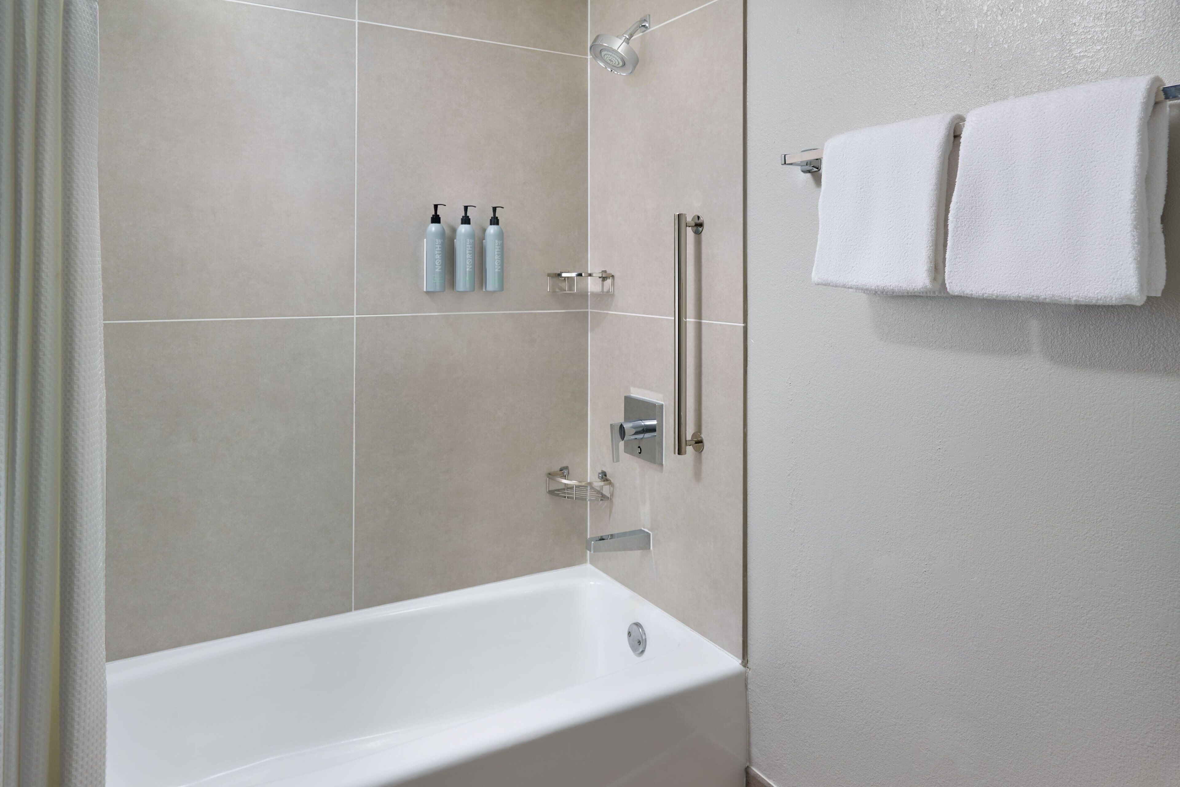 Un baño moderno con una bañera, una ducha y un perchero para toallas.