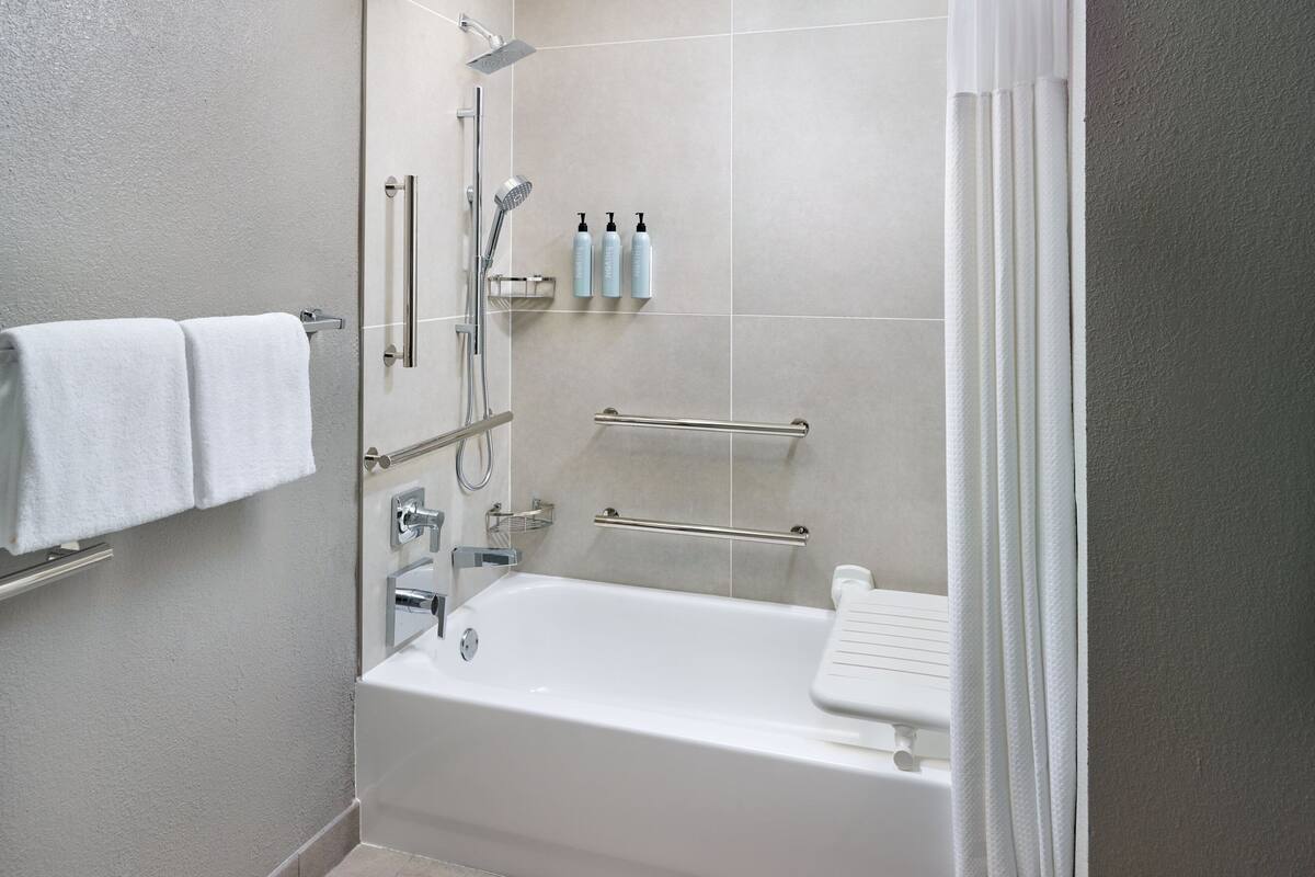 Un baño moderno con bañera, ducha y barras de apoyo.
