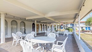 A covered outdoor area with white tables and chairs, arched windows, and string lights. - Motel 6 Spring Hill, FL - Weeki Wachee (Spring Hill)
