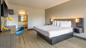 A modern hotel room with a large bed, a desk with a chair, a TV, and a mirror. - Motel 6 Spring Hill, FL - Weeki Wachee (Spring Hill)