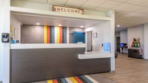 A reception area with a 'WELCOME' sign, a counter, a fire extinguisher, and a fire hose on the right. - Motel 6 Spring Hill, FL - Weeki Wachee (Spring Hill)