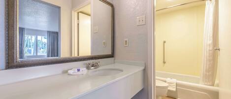 A bathroom with a double sink, a large mirror, a shower, and a toilet.