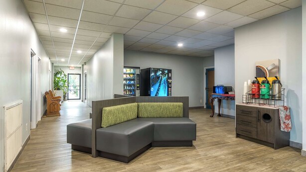 A modern lobby with a sectional sofa, a reception desk, and a vending machine. - Motel 6 Spring Hill, FL - Weeki Wachee (Spring Hill)