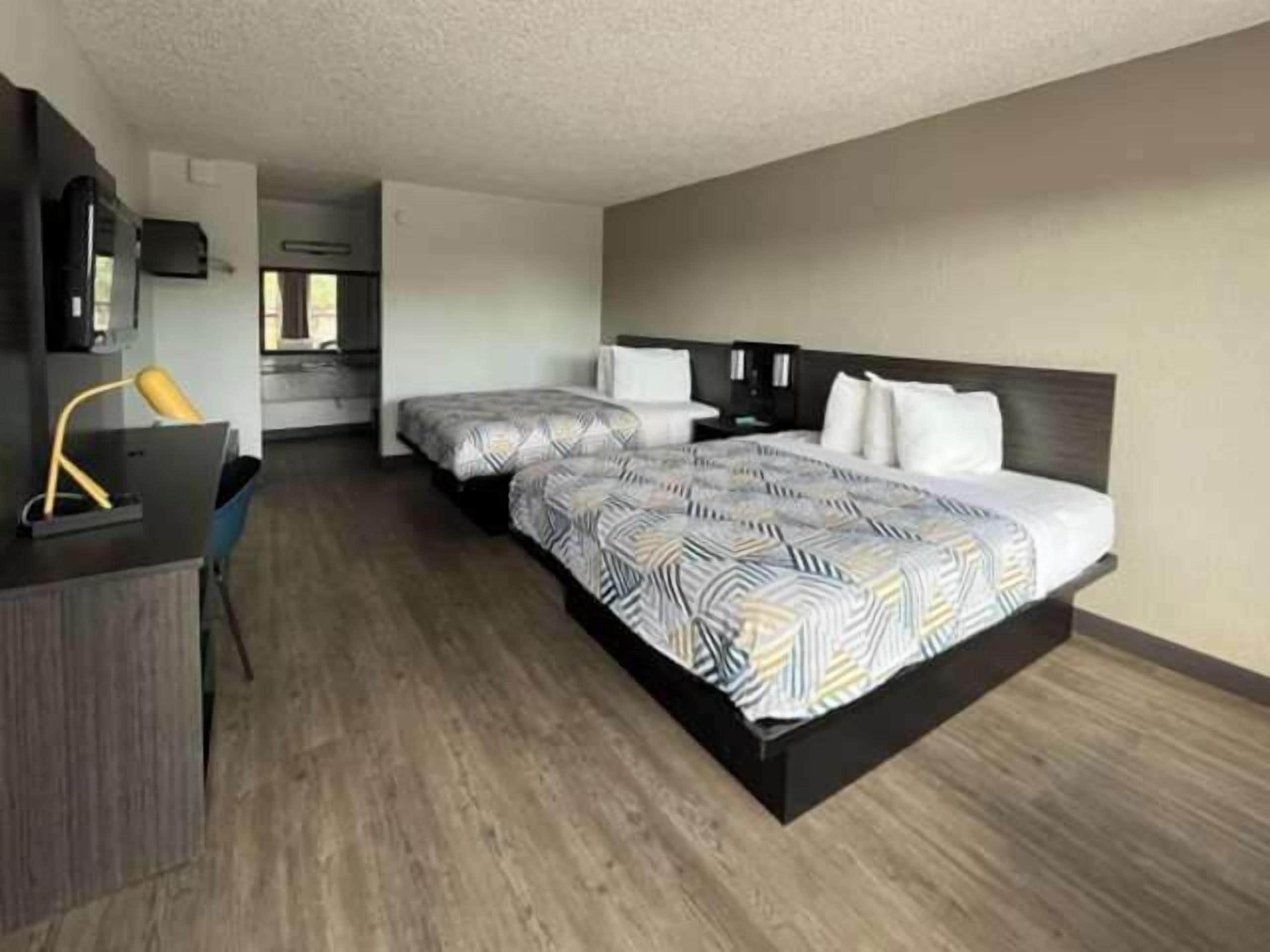 A modern hotel room with a large bed, a desk, and a chair.