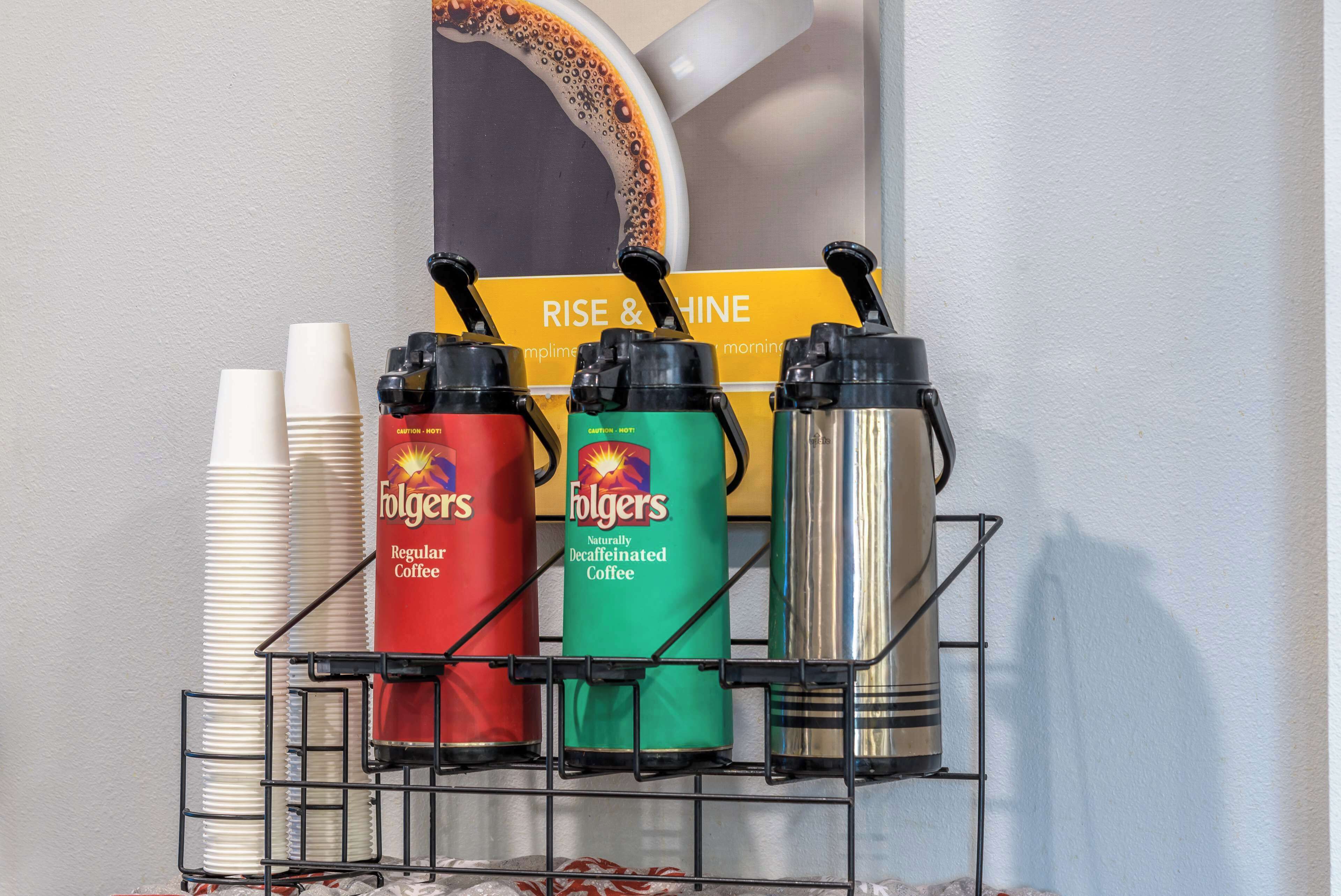 A coffee station with Folgers coffee dispensers and disposable cups.