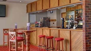 A bar area with wooden bar stools, a counter with a wine rack, and a seating area with chairs.