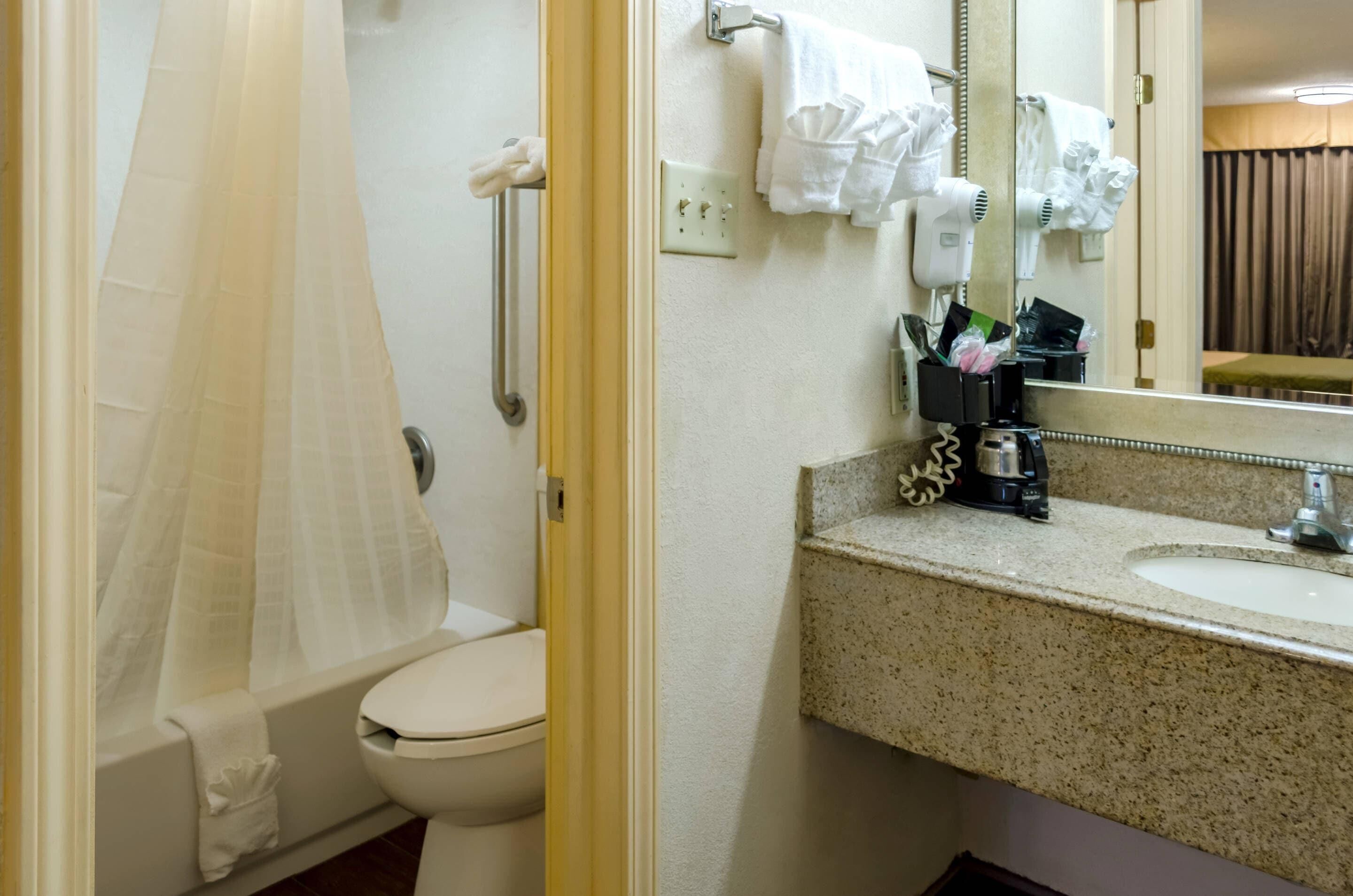 A bathroom with a toilet, shower curtain, towel rack, and a sink with a mirror.