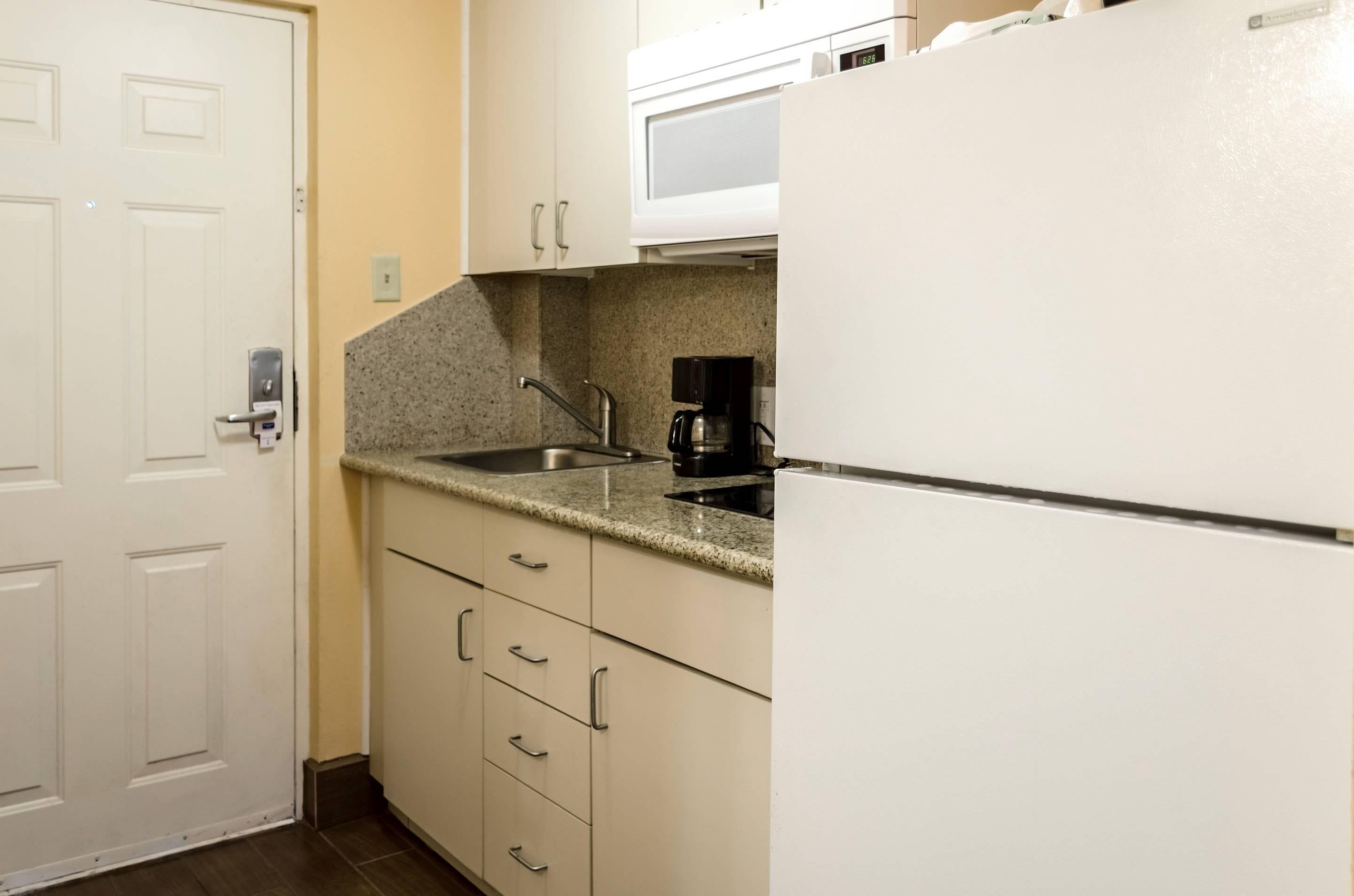 A kitchen with a white refrigerator, a coffee maker, and a microwave.