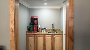 A small kitchen area with wooden cabinets, a coffee maker, and a sink. - Rodeway Inn Vicksburg (Vicksburg)