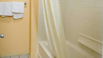 A bathroom with a bathtub, a shower curtain, and a towel rack with two towels.
