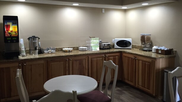 A kitchen with a coffee maker, toaster, microwave, and a beverage dispenser. There is a round table with chairs. - Rodeway Inn Vicksburg (Vicksburg)