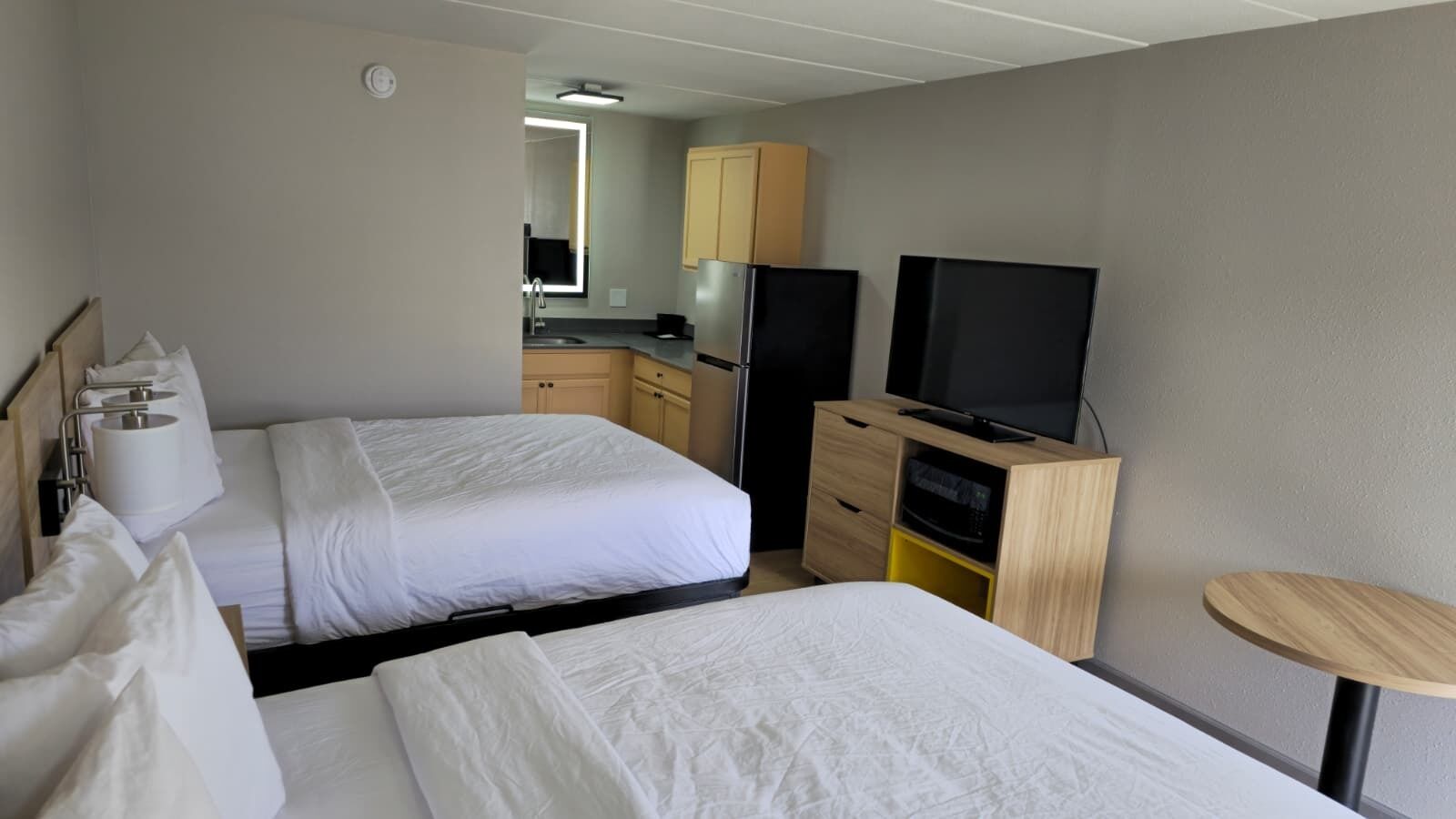 Une chambre d’hôtel avec deux lits, une télévision, une petite table et un coin cuisine.