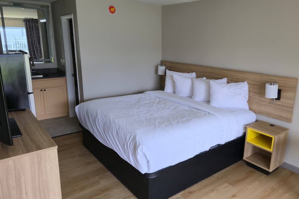 Een moderne hotelkamer met een bed, nachtkastje en een klein houten nachtkastje.
