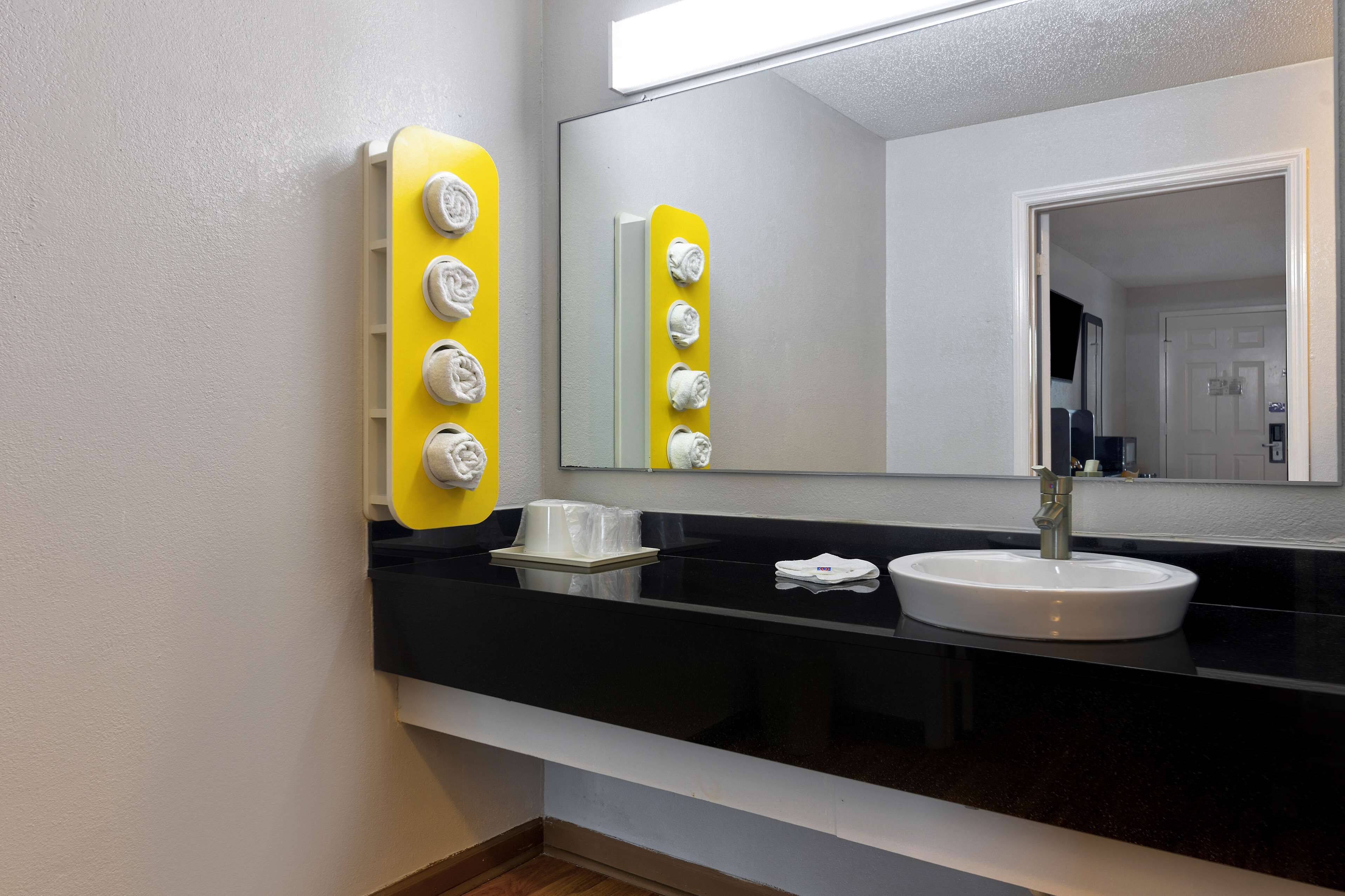 A modern bathroom with a black countertop, a white sink, and a mirror.