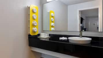 A modern bathroom with a black countertop, a white sink, and a mirror.