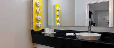 A modern bathroom with a black countertop, a white sink, and a mirror.