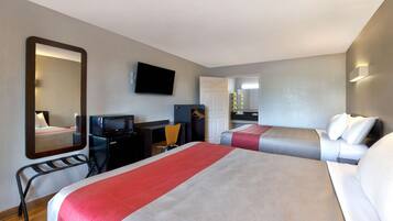 A hotel room with two beds, a desk, a chair, a TV, and a mirror.