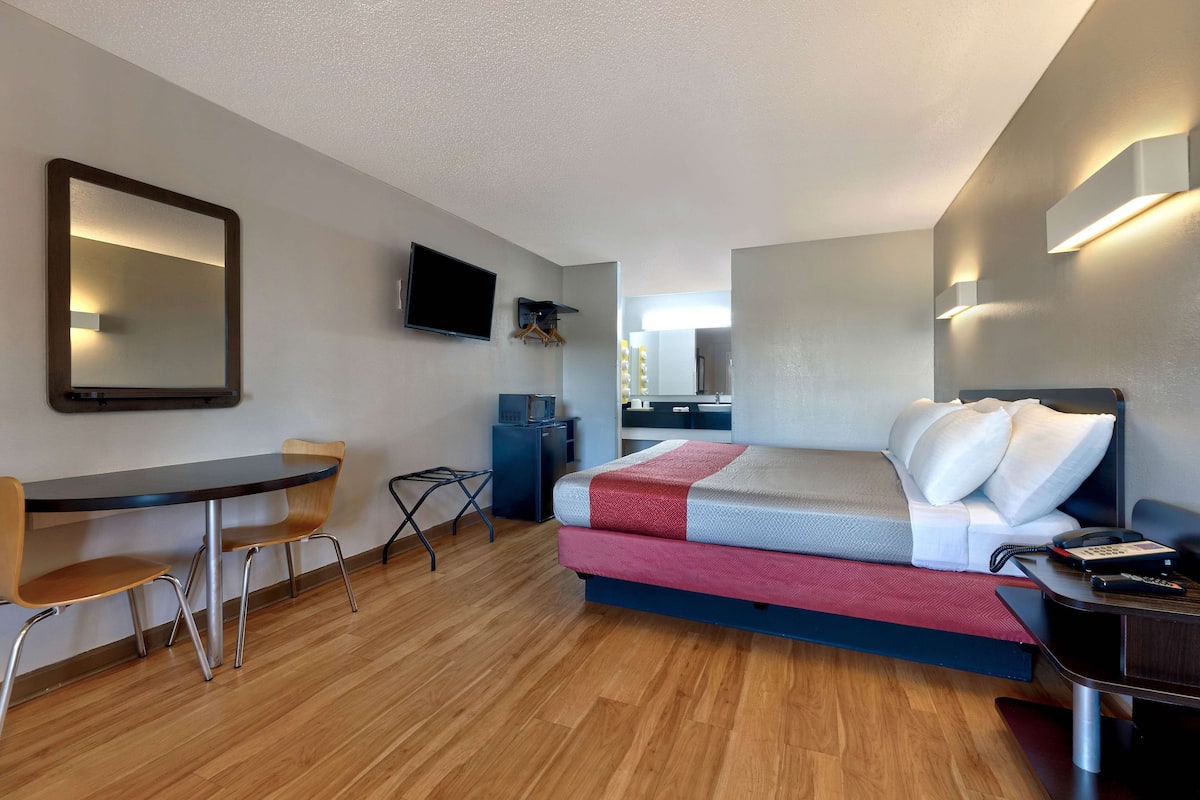 Een hotelkamer met een bed, een bureau, een stoel, een televisie en een klein tafeltje.