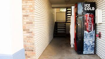 A narrow hallway with brick walls and a Coca-Cola vending machine labeled "ICE COLD".