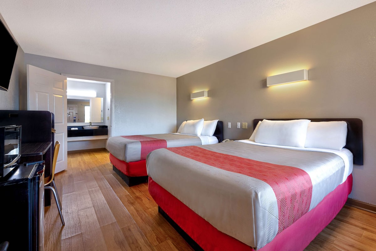 Een hotelkamer met twee bedden, een bureau en een stoel.