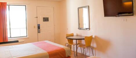 Habitación de hotel con dos camas, un escritorio, una silla, un televisor y una puerta.