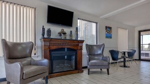 Un salon doté d’une cheminée, de deux fauteuils en cuir, d’un téléviseur et d’un coin repas avec une table et des chaises.