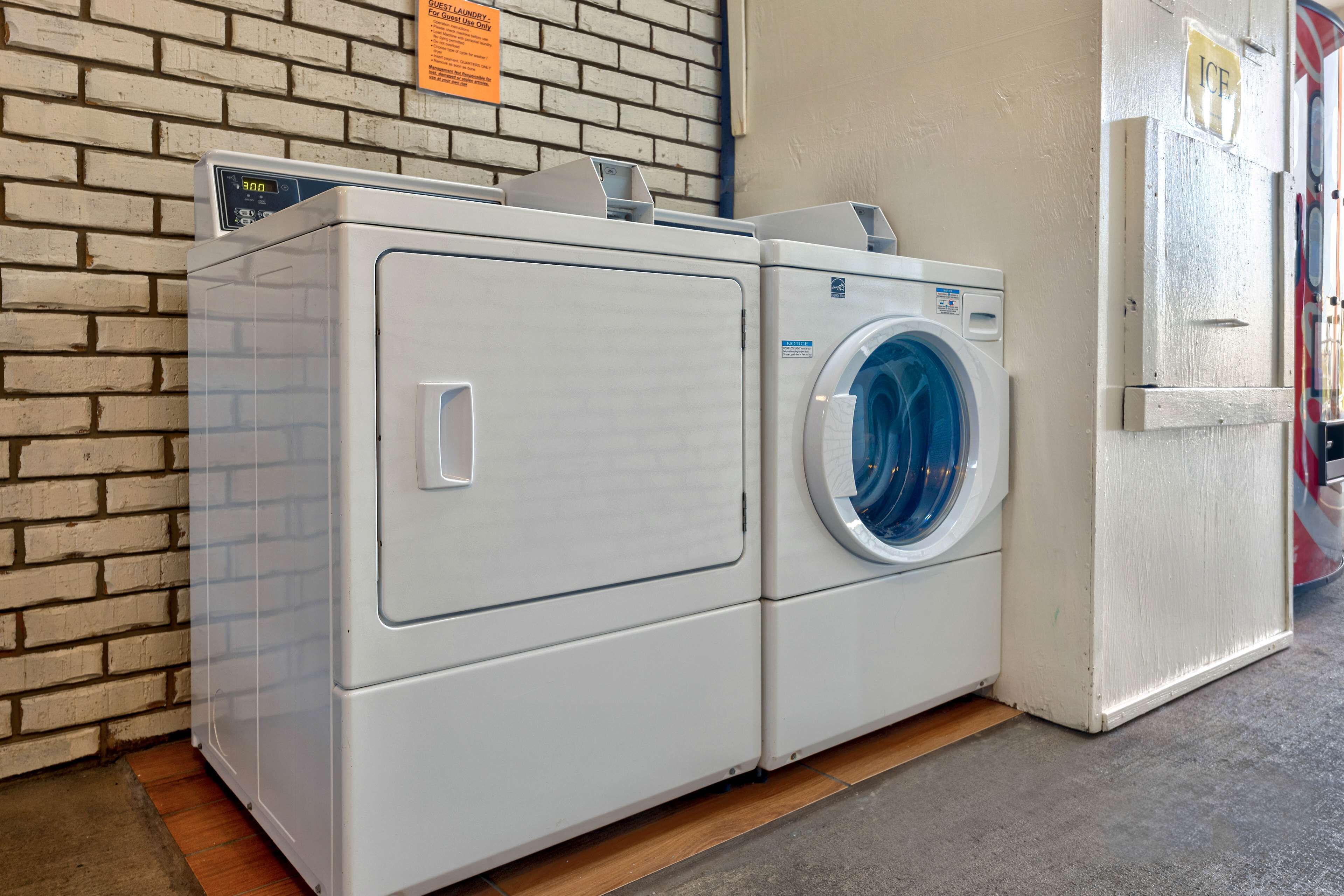A row of white stacked washer and dryer units against a brick wall.