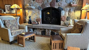 A cozy living room with a stone fireplace, leather armchairs, and a wooden coffee table.