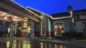 A hotel entrance with stone pillars, a Christmas tree, and string lights. - Canal Park Lodge (Duluth)