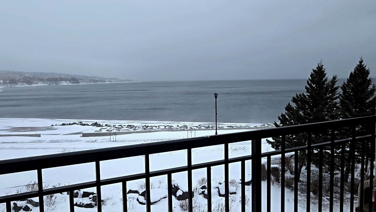 Paisaje nevado con vista al mar y una costa lejana.