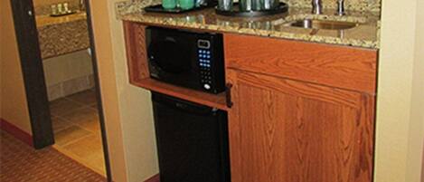 A compact kitchen with a microwave, coffee maker, and a sink.