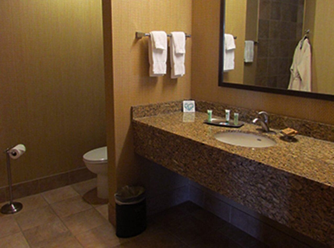 A bathroom with a granite countertop sink, a mirror, and two white towels hanging on a rack.