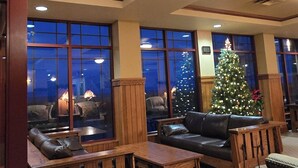 A lobby with wooden furniture, a Christmas tree, and large windows. - Canal Park Lodge (Duluth)
