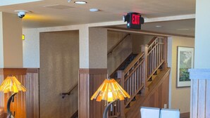 A spacious living area with a wooden coffee table, leather sofa, and a staircase leading to another level. - Canal Park Lodge (Duluth)