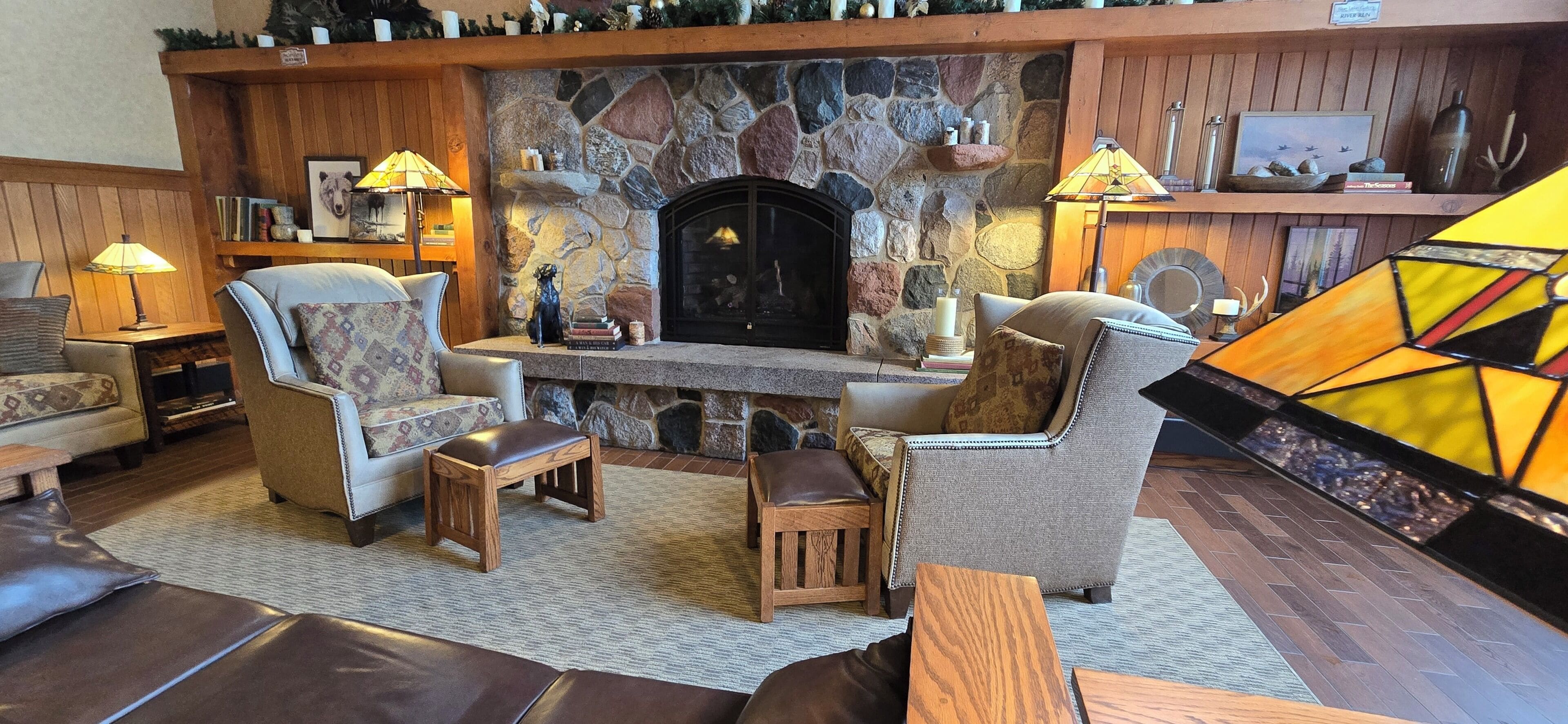 A cozy living room with a stone fireplace, leather sofas, and wooden side tables.