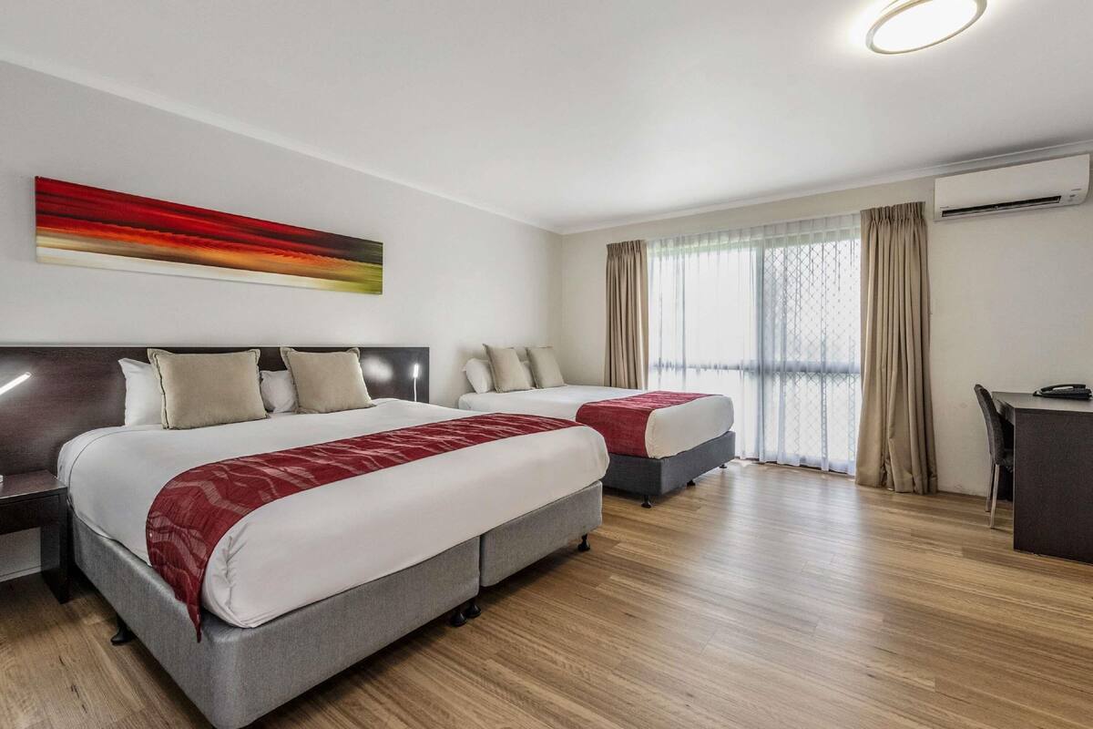 Une chambre d’hôtel avec deux lits, un bureau et un appareil de climatisation.