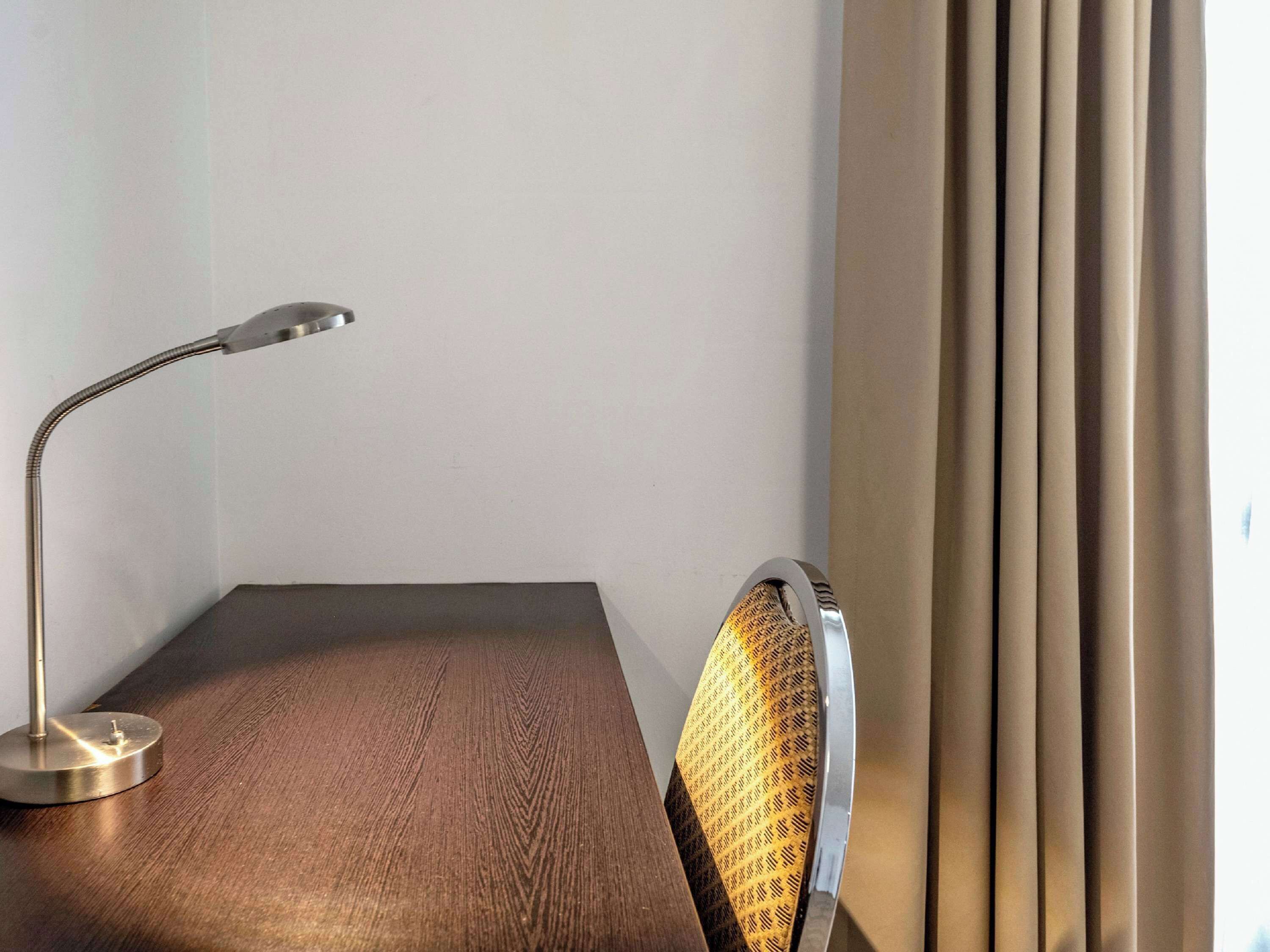 A corner of a room with a desk, a lamp, and a chair.