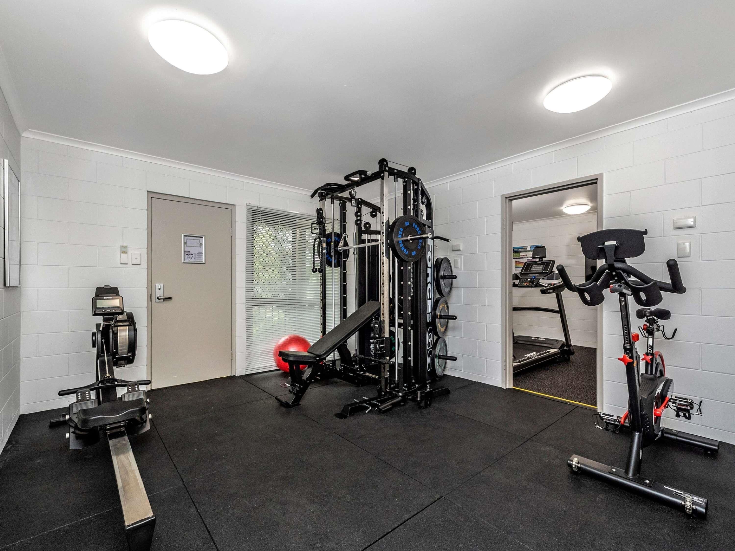 Ein Fitnessraum mit einer Gewichtbank, einem Ergometer und einem Kabelzuggerät.