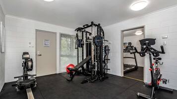 Ein Fitnessraum mit einer Gewichtbank, einem Ergometer und einem Kabelzuggerät.